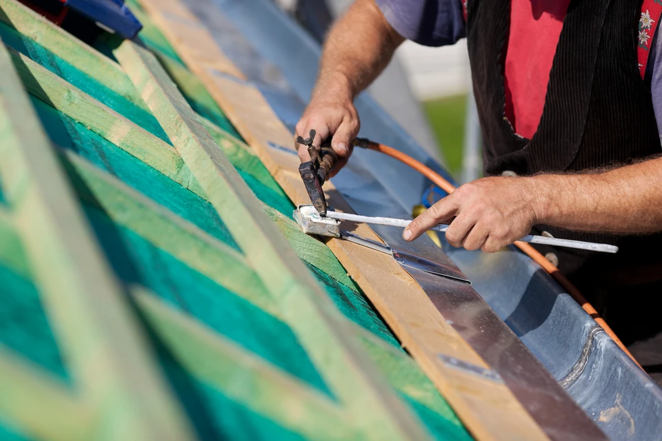 Artisan travaillant sur une toiture en rénovation, utilisant des outils de couverture