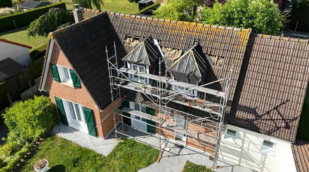 Vue aérienne d'une maison en briques rouges en cours de rénovation de toiture