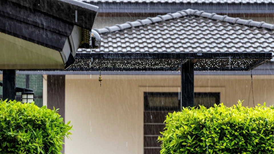 Pluie battante s'écoulant abondamment depuis une gouttière de toit résidentiel