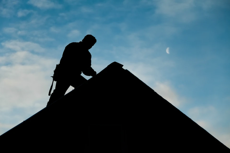 Artisan travaillant sur une toiture en rénovation, utilisant des outils de couverture